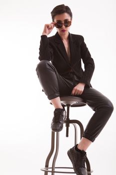 Caucasian fashion model holding sunglasses posing in studio over white background, Full body portrait.