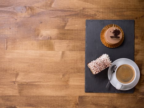 Top view of a cup of coffee near two different chocholate cakes on wooden table. Tasty desert. Delicious cake. Fresh cakes. Copy space available.