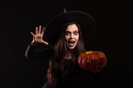 Caucasian young woman dressed up like a witch and screaming to the camera. Halloween dress. Scary lady on halloween.