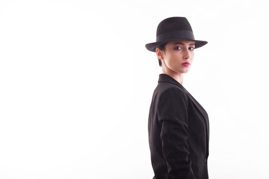 Fashionable caucasian young model posing with a black hat in studio over white background looking at the camera. Copy space available.