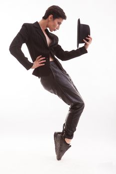 Beautiful young fashion model in elegant clothing posing like Michael jackson holding a stylish hat in studio over white background. Full body portrait of confident female.