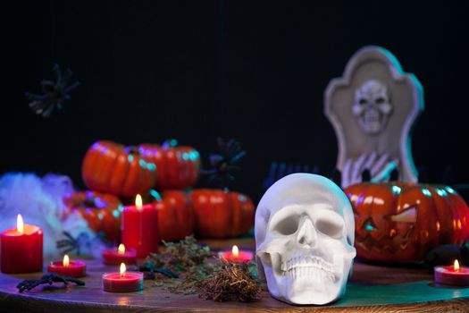 Spooky human skull with scary pumpkin behind on wooden table for halloween celebration. Halloween celebration.