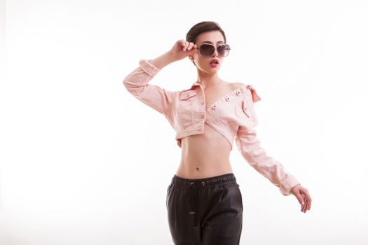 Classy fashion model posing in studio holding a pair of sunglasses in studio over white background. Stylish young female.