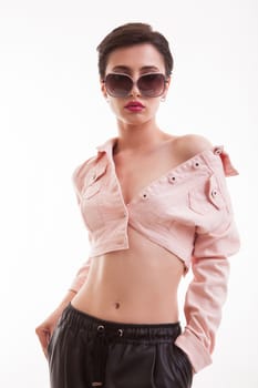 Stylish young female posing in studio wearing a pink jacket over white background. Girl with short hairstyle.