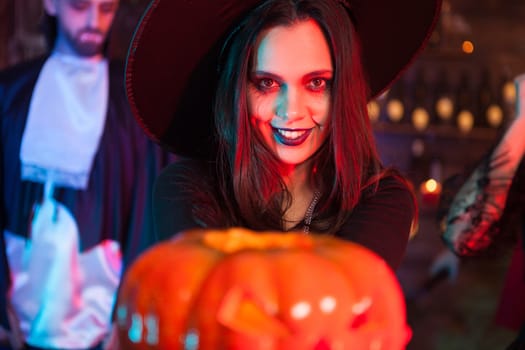 Sexy witch holding a magic pumpking with a scary expression for halloween party. Creepy witch.