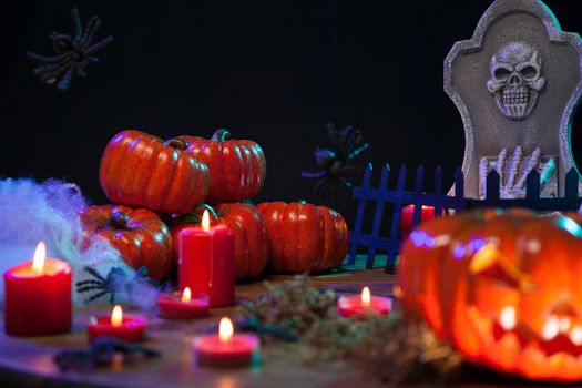 Haunted pumpkins on halloween with burning candles on a wooden table. Spooky mortuary stone.