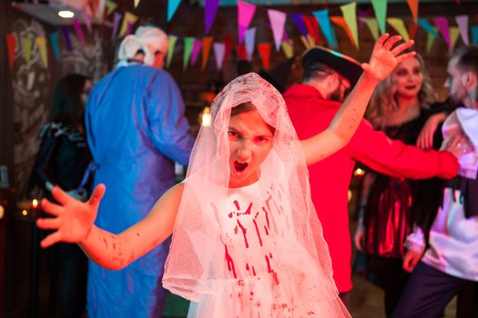 Portrait of little girl screaming dressed up like a bride for halloween. Monsters at a halloween party.