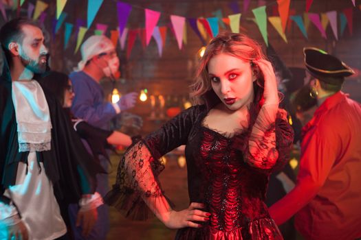 Beautiful woman dressed in a black dress for halloween celebration with a scary makeup. Girl with a scary looking at halloween party.