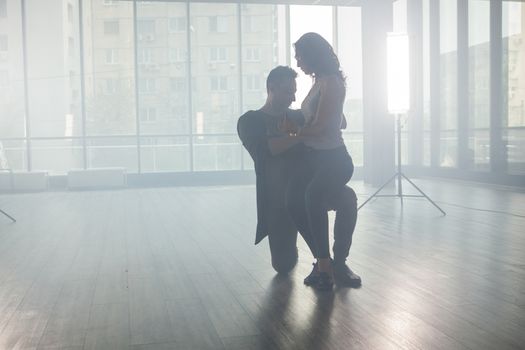 Active happy adults dancing kizomba in a dance room. Dancers silhouette. Skillful dancers.