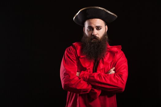 Handsome bearded man dressed up like a pirate for halloween carnival keeping his arms crossed and looking at the camera. Man with a long beard in a mariner costume.