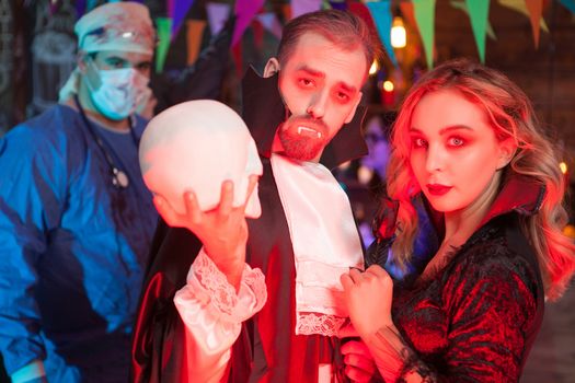 Attractive young man dressed up like Dracula with his beautiful girl for halloween party. Sexy woman dressed up like a witch for halloween.