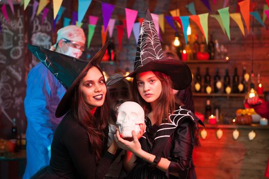 Crazy doctor and two beautiful witches celebrating halloween. Witches with beautiful dresses.