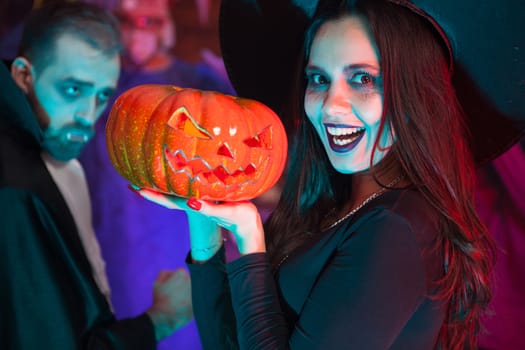 Creepy young woman dressed up in a witch costume for halloween. Friends celebrating halloween.