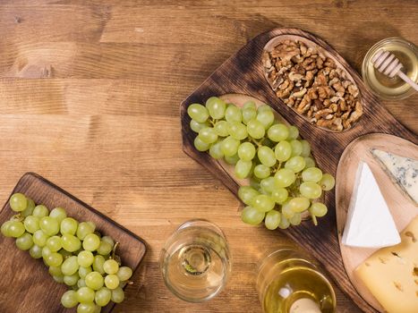 Top view of wolnuts next to fresh grapes on wooden plate in a vintage restaurant. Glas of white wine.