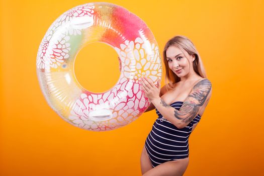 Pretty young woman in swimming suit playing with colorful swimming ring ready for summer vacation. Sensual woman in swimming suit.