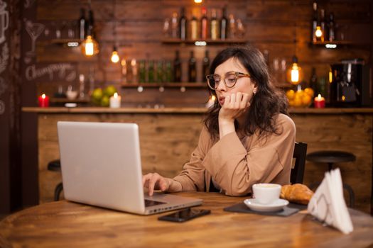 Portrait of beautiful young woman working on her laptop in a coffee shop. Portrait of smart woman working on laptop. Woman working on her laptop in a coffee shop with wifi.