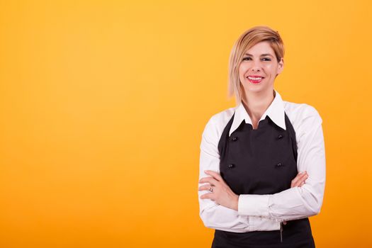 Barman woman looking at the camera and smiling over yellow background. Skilled coffeemaker. . Attractive woman.
