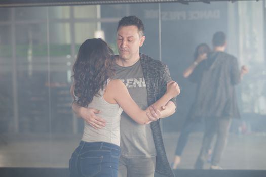 Attractive couple dancing kizomba in front of a big mirror. Beautiful performance. Talented couple.