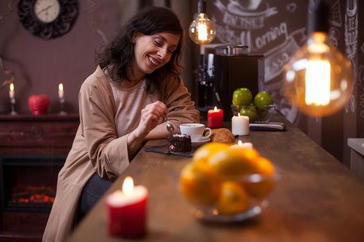 Portrait of beautiful young woman eating cake at the bar counter in a coffee shop. Delicious cake eating by beautiful woman smiling.