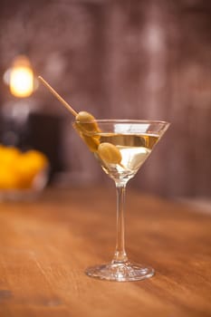 Transparent glass filled up with dry white martini on a counter bar. Refined liquor. Fresh drink.