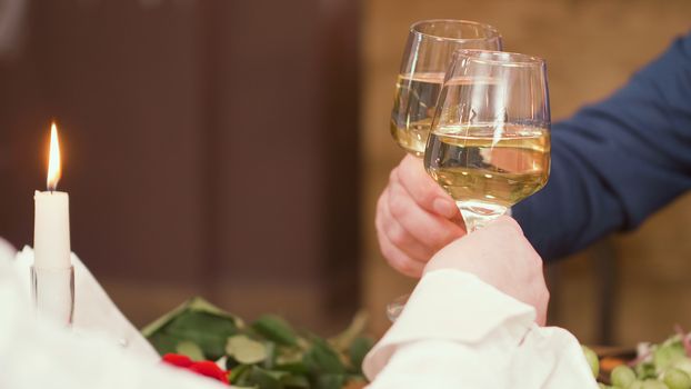 Senior couple raising toast during mealtime in a restaurant. Relaxed couple. Drinking wine.