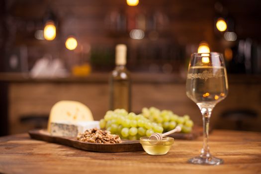 Bowl of delicious golden honey next to a glass of white wine. French cheese. Fresh grapes.