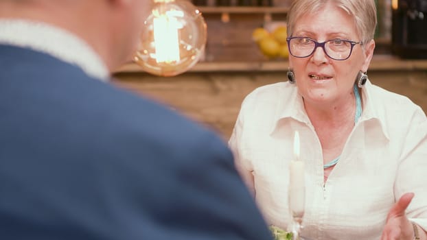 Senior woman looking with love at her husband during dinner in a restaurant. Mature woman. Woman in her sixties.