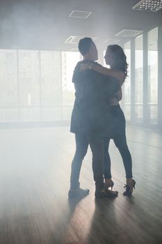 Couple in love dancing kizomba in dance room full of smoke. Persistent dancing. Beautiful performance.