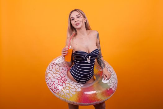 Gorgeous young woman with slim and fit body inside a swimming ring over a yellow background. Attractive caucasian woman. Woman in luxury swimming suit.