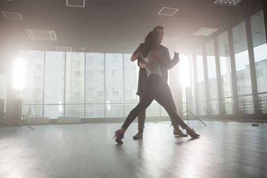 Kizomba dancers showing their passion for dancing kizomba in front a dancing room with big windows in the background. Passionate dancers.