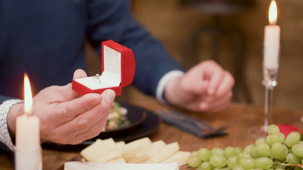 Close up of weeding ring holed by a senior man at table in a restaurant. Man in his sixties.