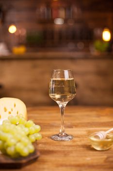 One glass of finest white wine with parmesan cheese. Honey bowl. Delicious grapes.