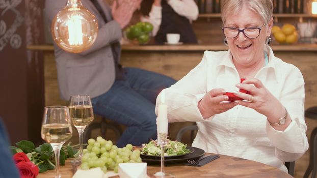 Happy senior woman with the ring that her husband gave her during mealtime in a restaurant. Senior couple. Woman in her sixties.