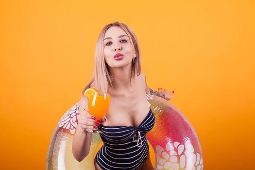 Attractive young woman giving a kiss to the camera over yellow background. Beautiful woman. Summer vibe.