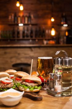 Cold beer with classic burgers on a restaurant wooden table. Delicious food.