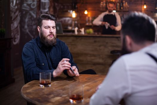 Handsome bearded men playing card in a pub and drinking whiskey. Attractive men. Stylish beard