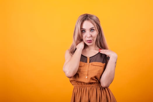 Attractive caucasian woman looking at the camera over yellow background. Happy young woman. Fashionable woman.