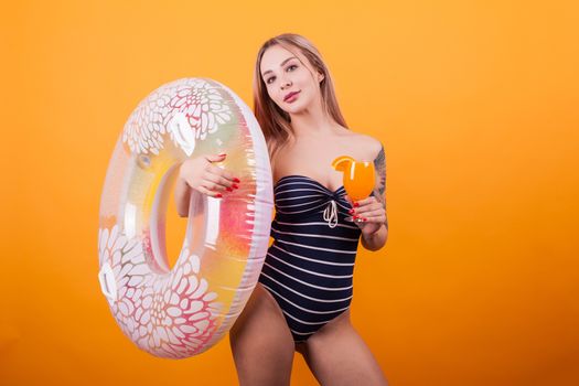 Young sexy caucasian woman with swim ring ready for vacation over yellow background. Ready for pool party. Summer body.