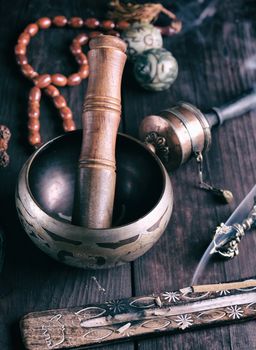 copper singing bowl and a wooden stick on a brown table, vintage toning