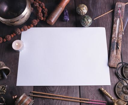 blank white sheet in the middle of religious objects for meditation, relaxation and massage on a brown wooden background 