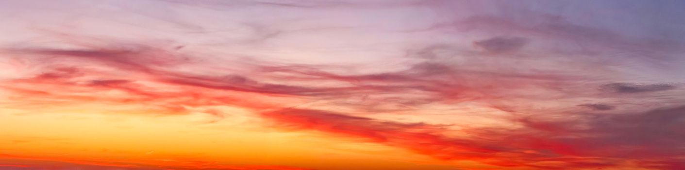 Beautiful high resolution panorama of orange and red sunset clouds in the evening sky.