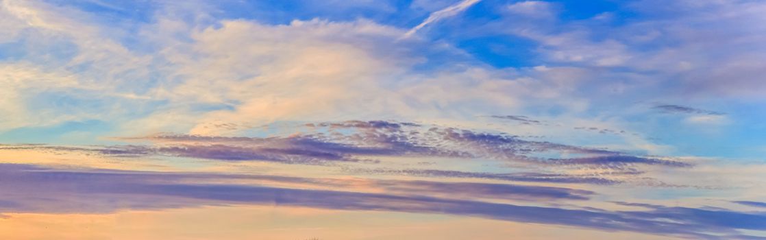 Beautiful high resolution panorama of orange and red sunset clouds in the evening sky.