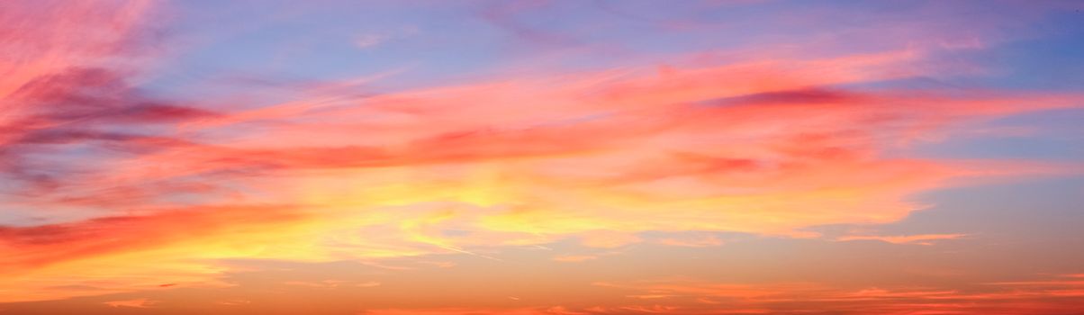 Beautiful high resolution panorama of orange and red sunset clouds in the evening sky.