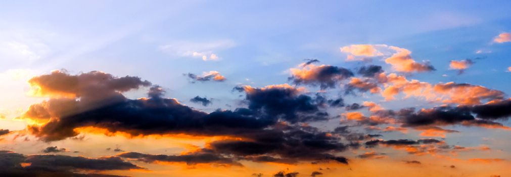 Beautiful high resolution panorama of orange and red sunset clouds in the evening sky.