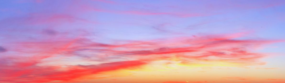 Beautiful high resolution panorama of orange and red sunset clouds in the evening sky.