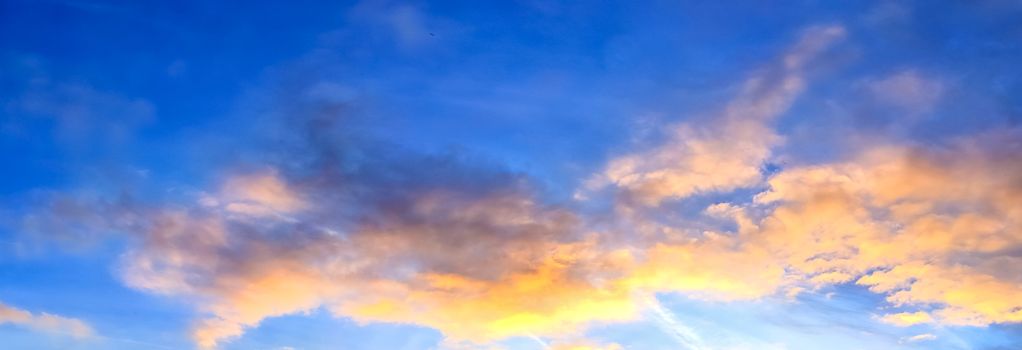 Beautiful high resolution panorama of orange and red sunset clouds in the evening sky.