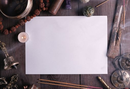 blank white sheet in the middle of religious objects for meditation, relaxation and massage on a brown wooden background