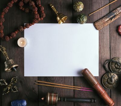 blank white sheet in the middle of religious objects for meditation, relaxation and massage on a brown wooden background