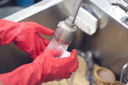 Close up dish washing with red rubber gloves, selective focus