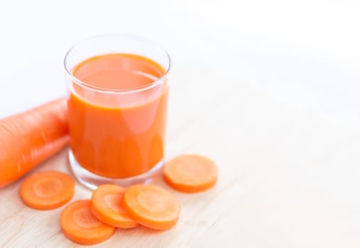 Closeup top view glass of carrot juice and fresh carrot with over light, selective focus